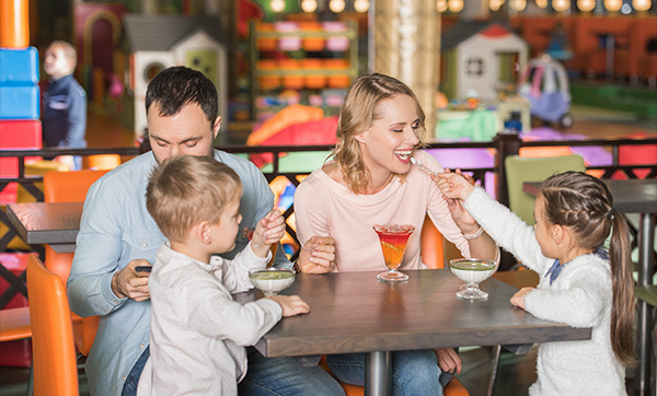 a family at a table in a colorful play area enjoying drinks and dessert together with children sharing food moments of happiness and fun for six